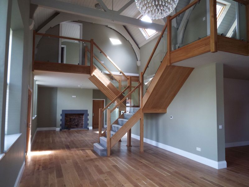 Double-height living space with oak staircase, glass balustrade and galleried landing